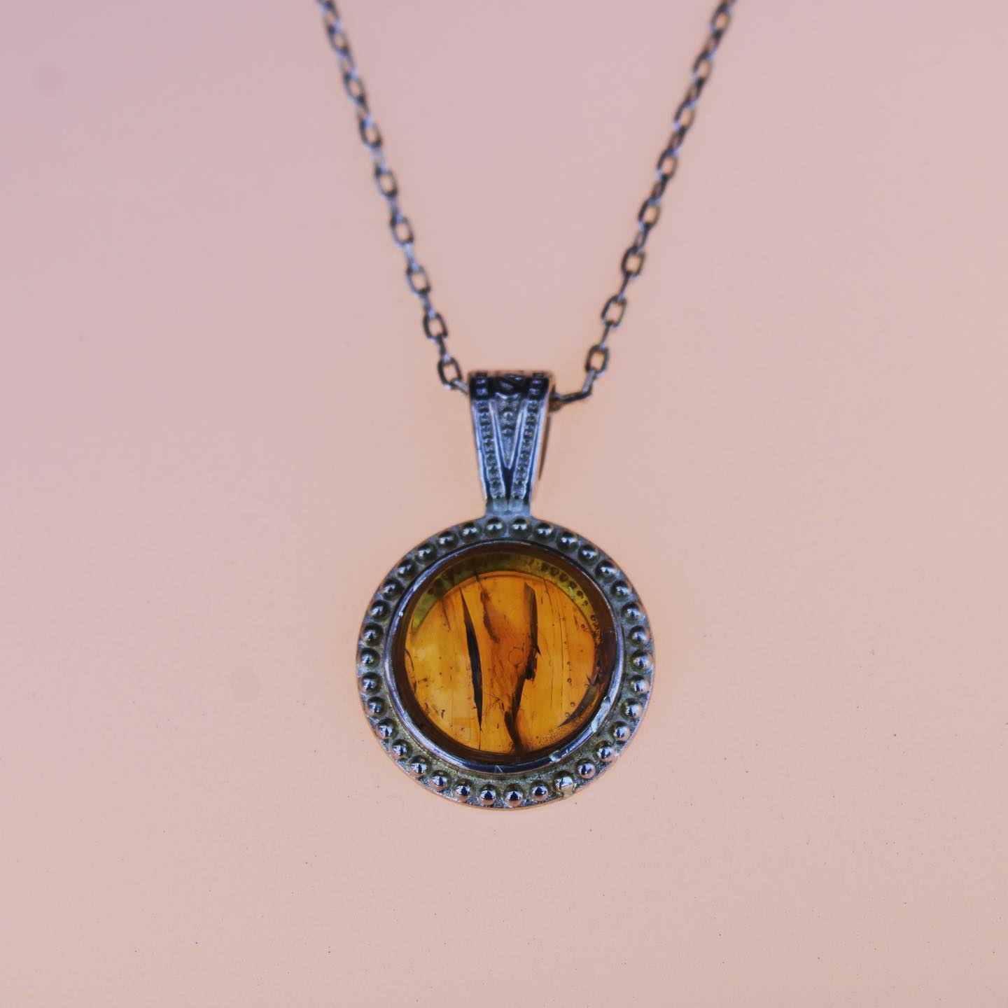 Necklace with rich, beautiful clear yellow Baltic Amber, hand polished to a 14mm round cabochon and set in a silver plated setting with 19 inch chain, on pink, light