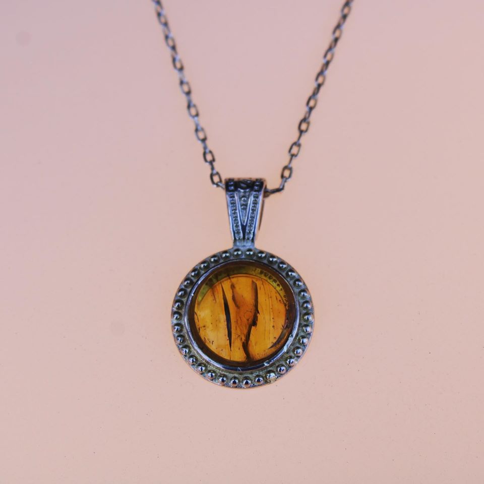 Necklace with rich, beautiful clear yellow Baltic Amber, hand polished to a 14mm round cabochon and set in a silver plated setting with 19 inch chain, on pink, darker