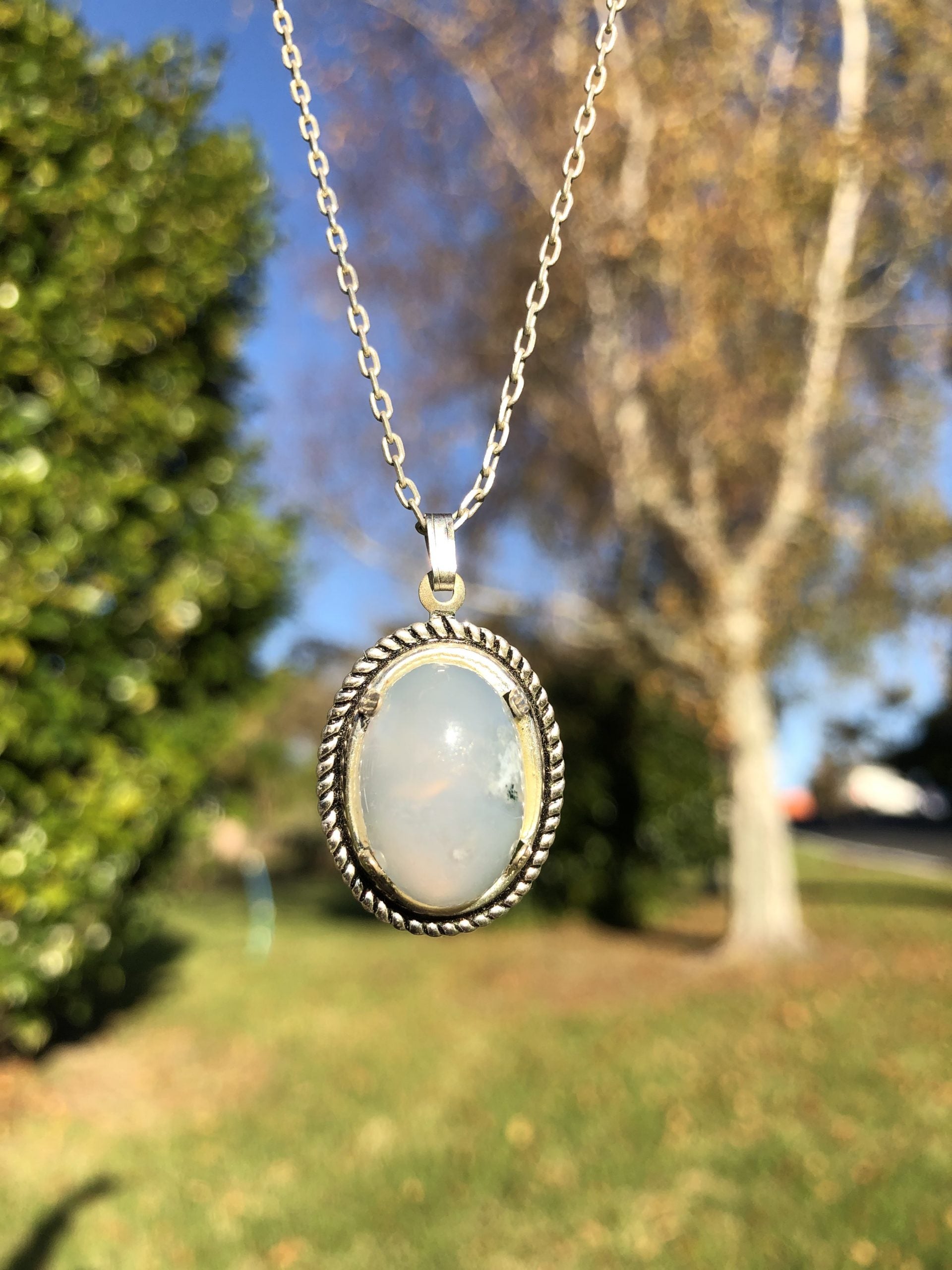 Necklace of Namibian Blue Lace Agate, with delicate blue and white stripes, hand polished to a 25x18mm cabochon and set in silver plated setting with 19 inch chain, front