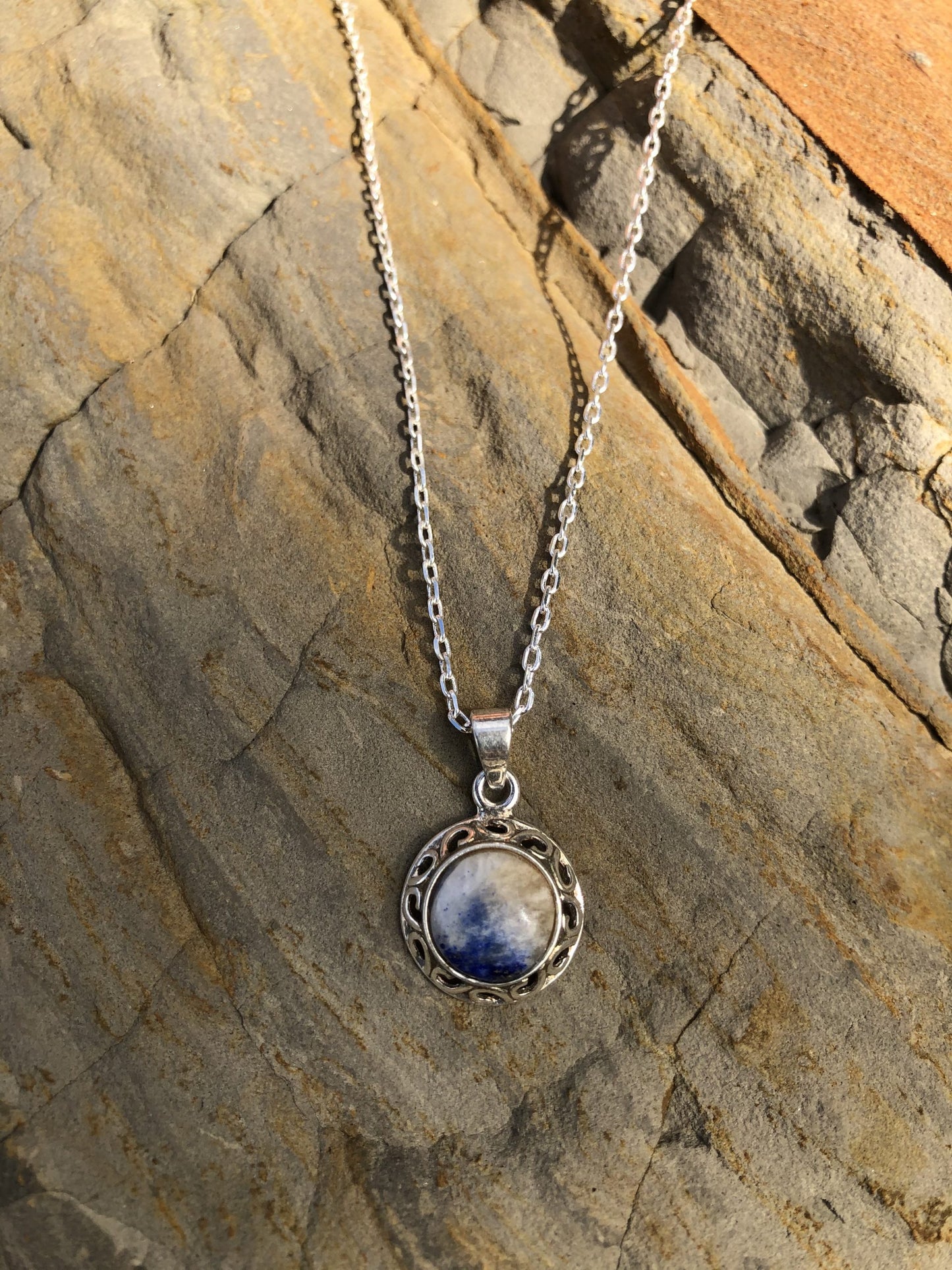 Necklace with delicate blue lapis lazuli with white quartz, hand cut to a 10mm round cabochon and set in silver plated setting with 19 inch chain.