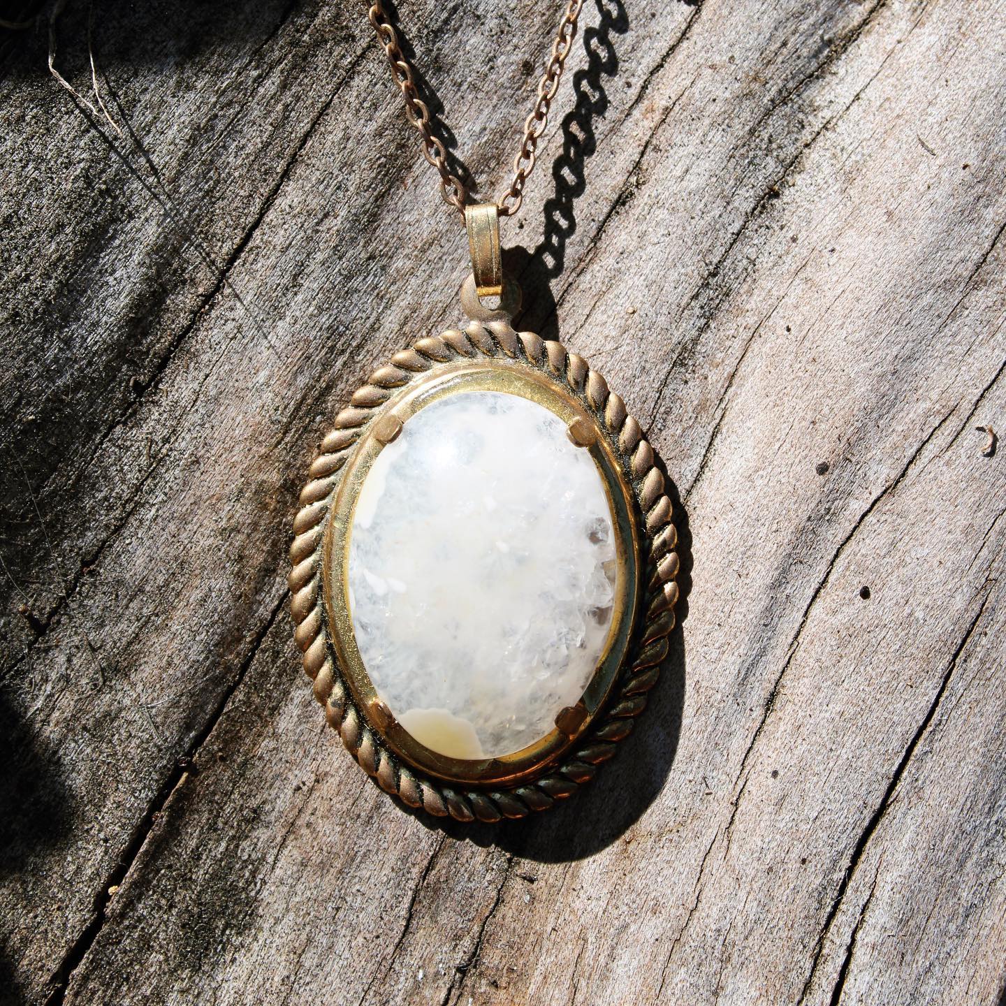 Necklace of sparkling New Zealand quartz from the heart of a solid geode, hand polished to a 25x18mm oval cabochon and set in a gold plated setting with 19 inch chain on driftwood, darker