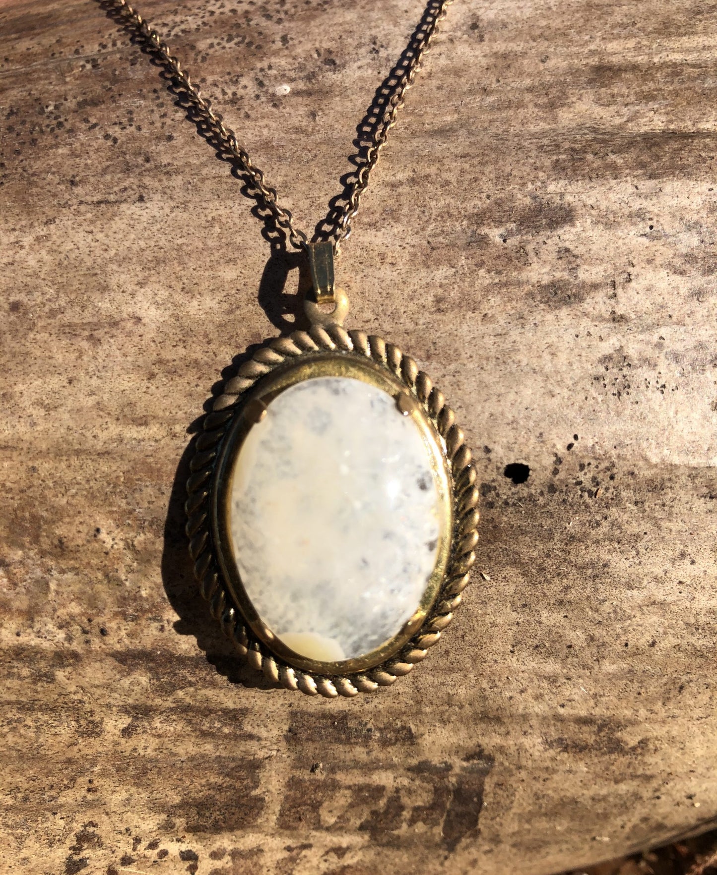 Necklace of sparkling New Zealand quartz from the heart of a solid geode, hand polished to a 25x18mm oval cabochon and set in a gold plated setting with 19 inch chain, on wood, front