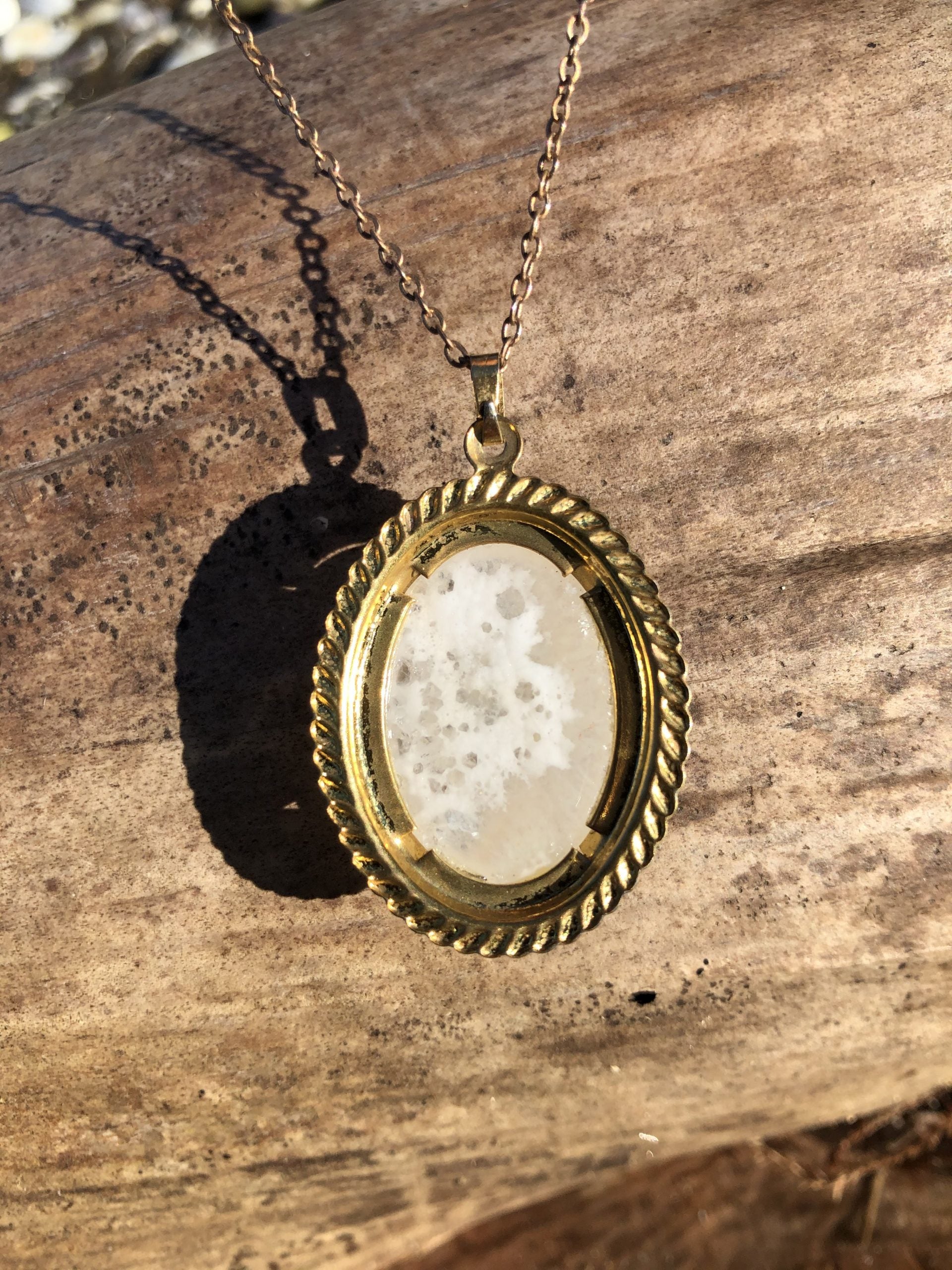 Necklace of sparkling New Zealand quartz from the heart of a solid geode, hand polished to a 25x18mm oval cabochon and set in a gold plated setting with 19 inch chain, on wood, back