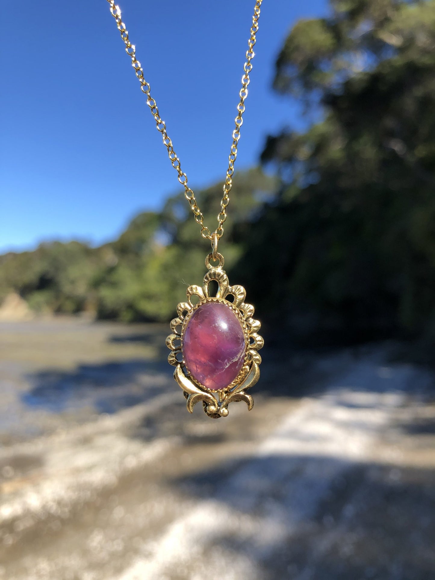 Necklace with rich, dark purple Amethyst, hand polished to a 16x12mm oval cabochon and set in a gold plated setting with 19 inch chain on trees