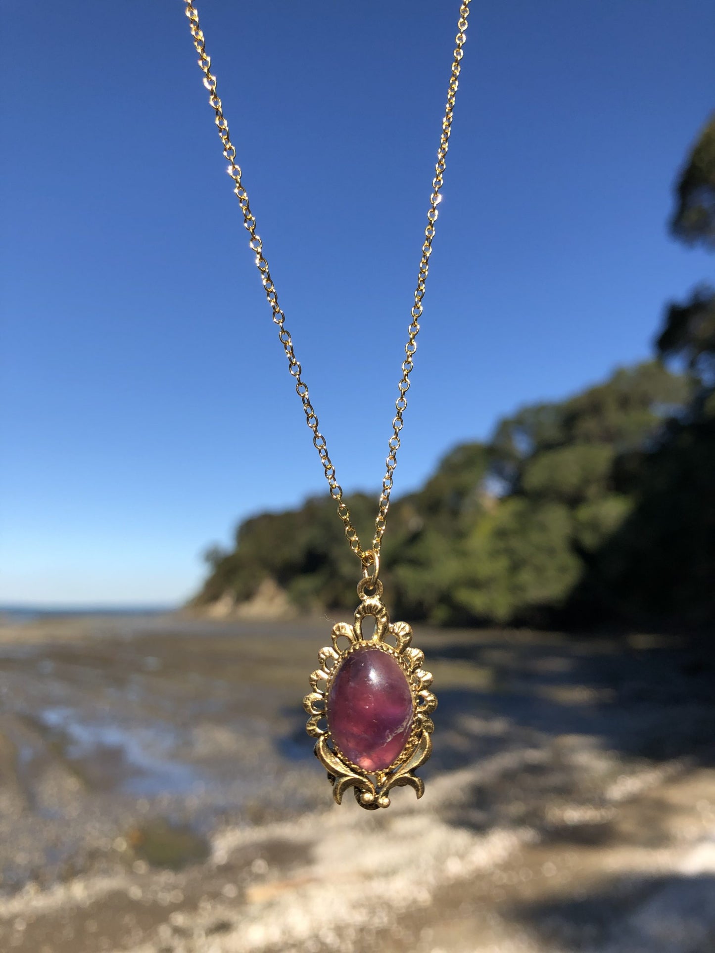 Necklace with rich, dark purple Amethyst, hand polished to a 16x12mm oval cabochon and set in a gold plated setting with 19 inch chain on beech