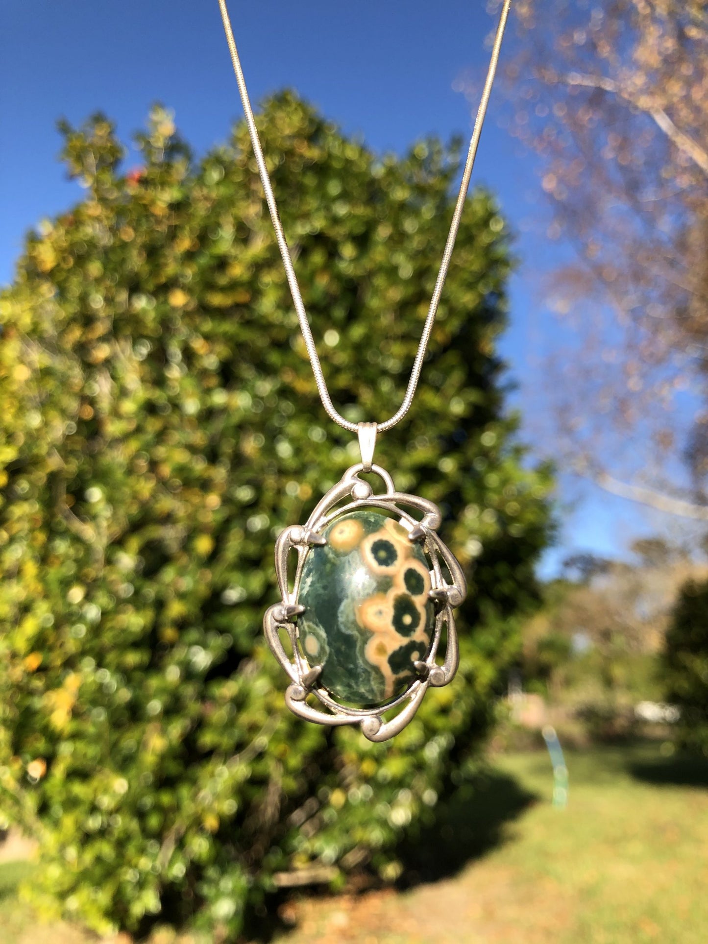 Necklace with Ocean Jasper from Madegascar, green and yellow spots, hand polished to a 25x18mm cabochon and set in a Sterling silver setting with 24 inch Sterling silver snake chain on tree