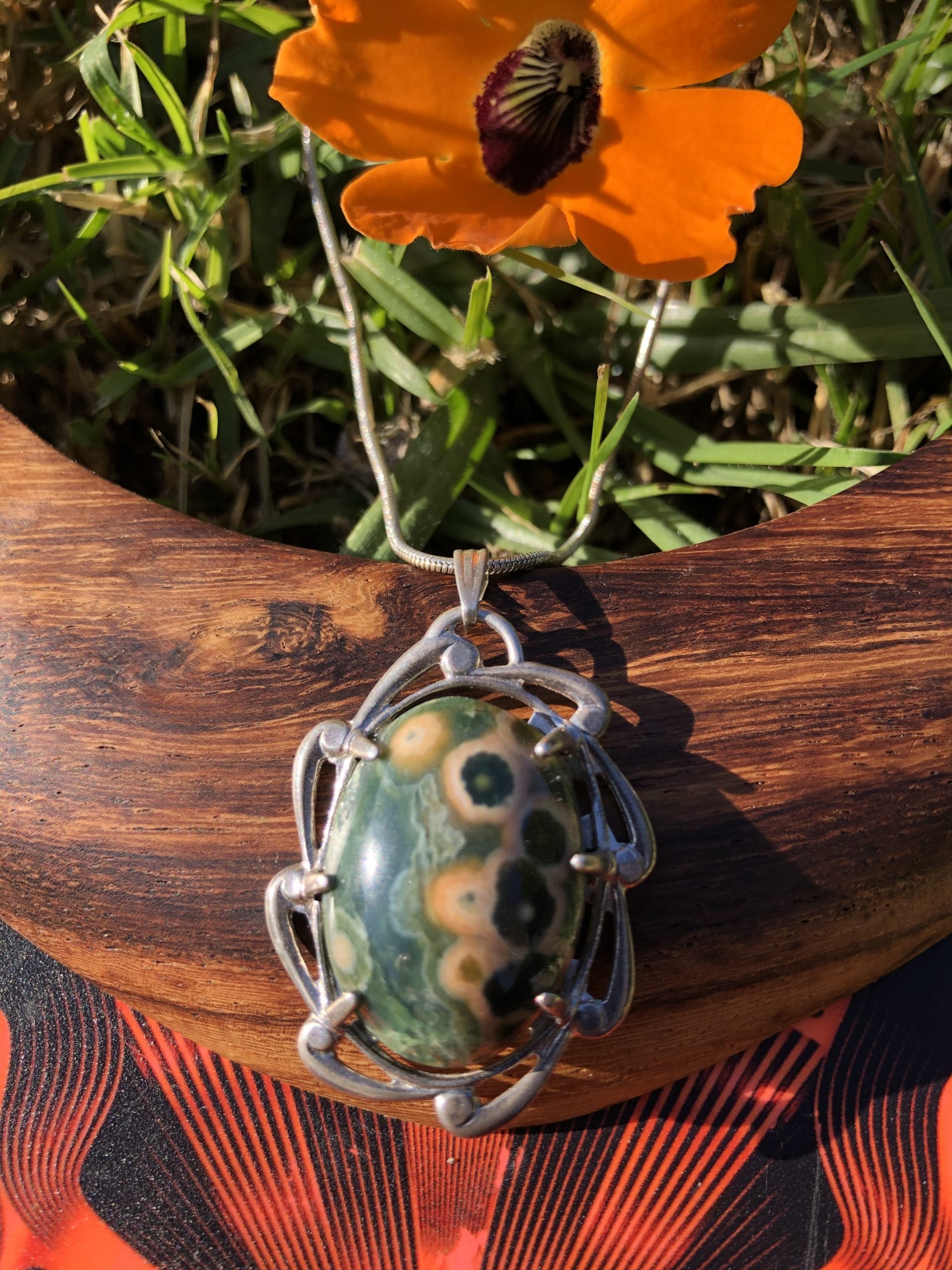 Necklace with Ocean Jasper from Madegascar, green and yellow spots, hand polished to a 25x18mm cabochon and set in a Sterling silver setting with 24 inch Sterling silver snake chain on wood