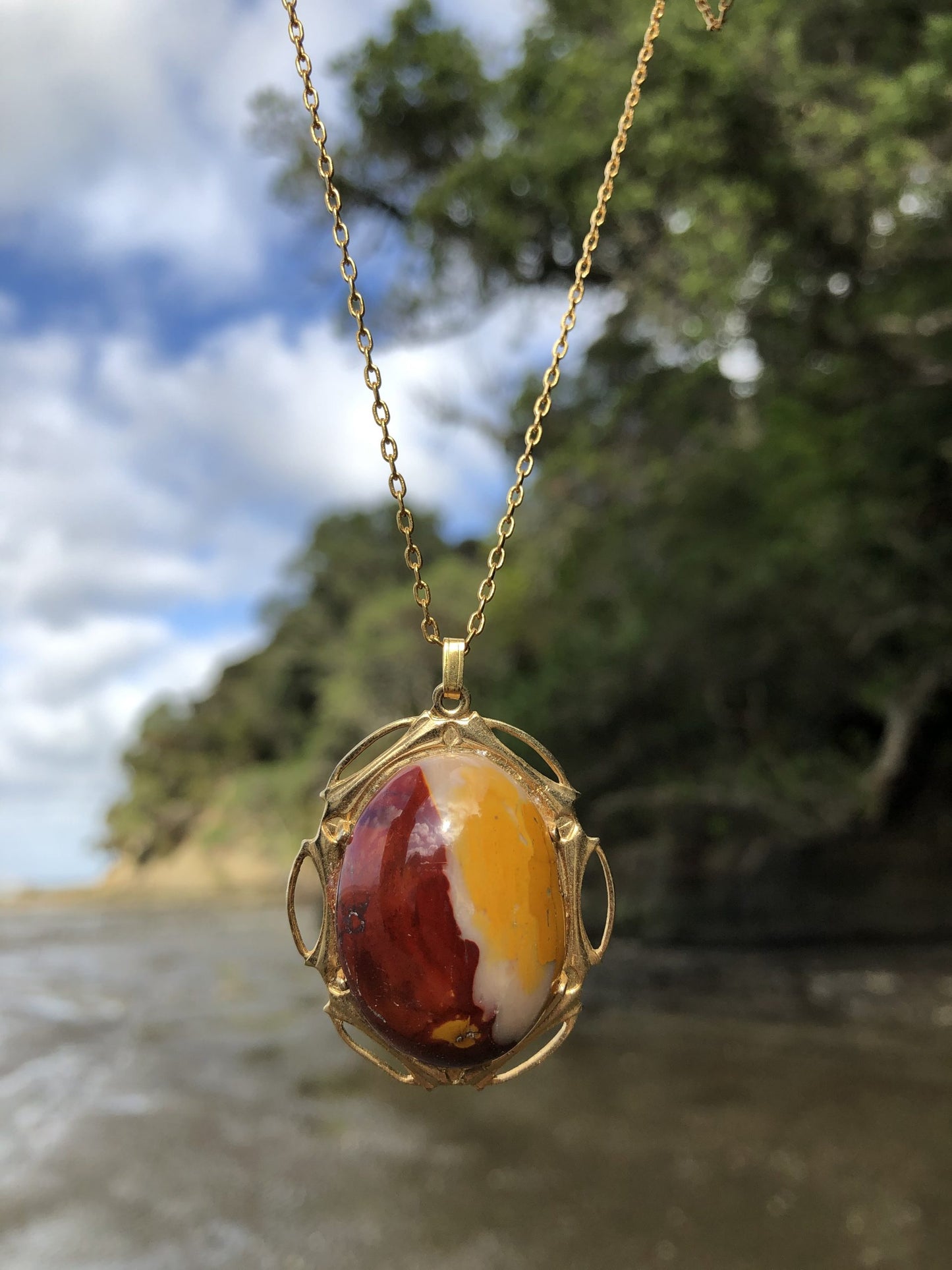 Necklace of Mookaite from Western Australia. This stone includes all 3 classic colors of Mookaite, red, yellow, and white. I hand polished this stone to a 30x22mm cabochon, set in gold-plated setting with 19 inch chain  on beach