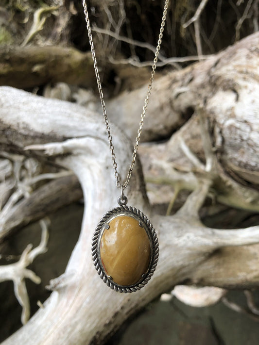 Necklace with natural petrified wood from Coromandel, New Zealand with subtle brown and tan tones along the grain lines, hand polished to a 25x18mm cabochon and set in a silver-plated setting with 19 inch chain on driftwood