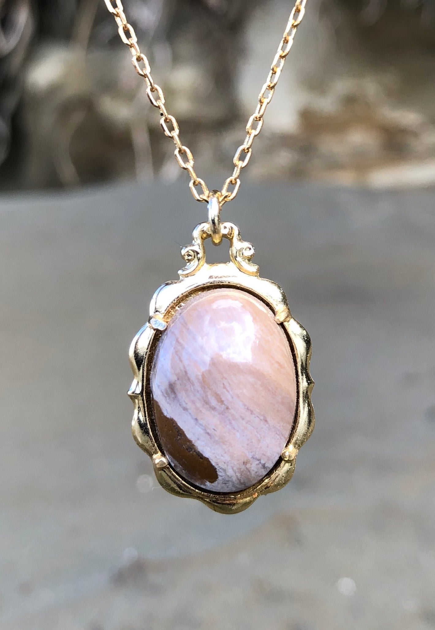 Necklace with subtle browns, tans and grey jasper from India. The stone is hand polished to a 20x15mm cabochon and set in a gold-plated setting with 19 inch chain.